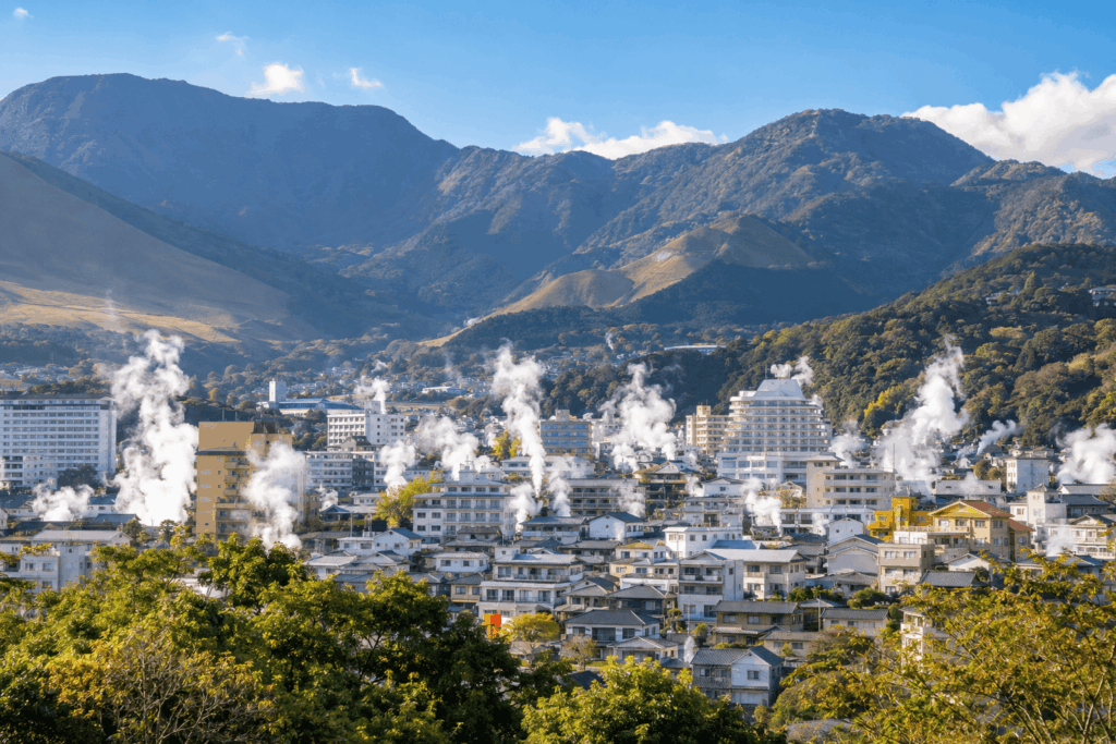 別府市の温泉街に立ちのぼる湯けむりと山々の風景